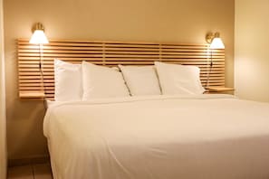 A neatly made bed with white bedding and a wooden headboard with horizontal slats. - The Palms Resort (South Padre Island)