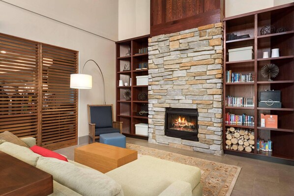 A cozy living room with a stone fireplace, wooden shelves, and a comfortable seating area.