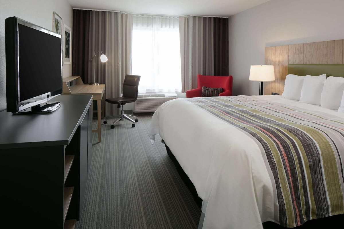 Ein Hotelzimmer mit Bett, Schreibtisch mit Fernseher, Stuhl und Lampe.