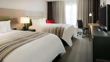 Habitación de hotel con dos camas, un escritorio con ordenador, televisión y una silla.