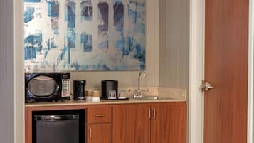 A kitchen with a microwave, coffee maker, and sink.