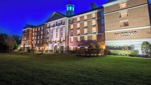 Un hotel Courtyard Marriott con fachada de ladrillo, múltiples ventanas y una torre con luces iluminadas.