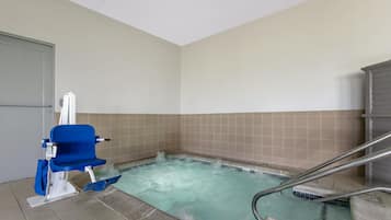 A small, rectangular hot tub with a blue chair and metal railings.