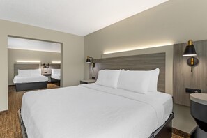A hotel room with a large bed, bedside tables, a mirror, and a wall-mounted lamp. - Best Western Plus Omaha Airport Inn (Carter Lake)