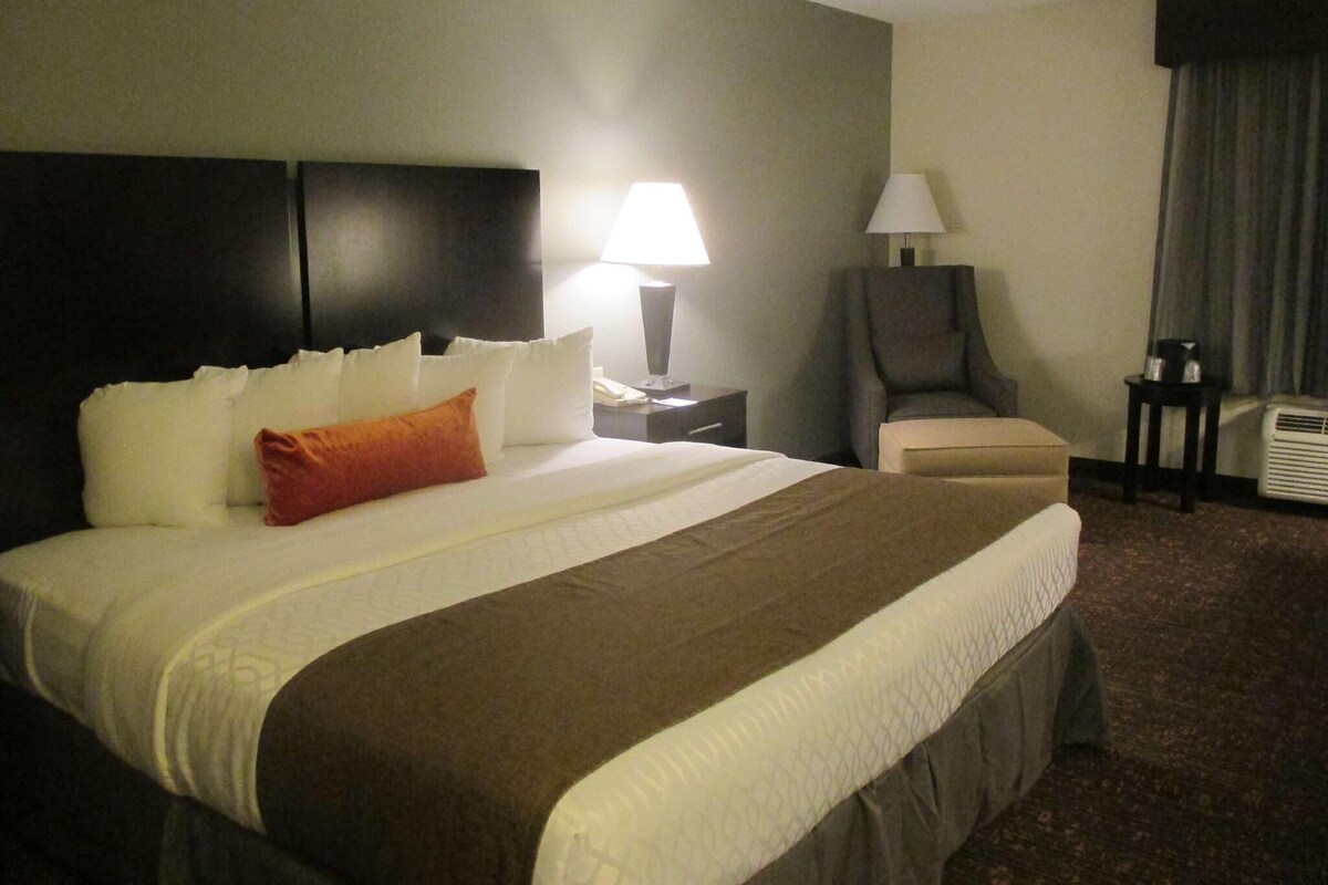 A hotel room with a large bed, two bedside tables, a chair, a desk, and a lamp.