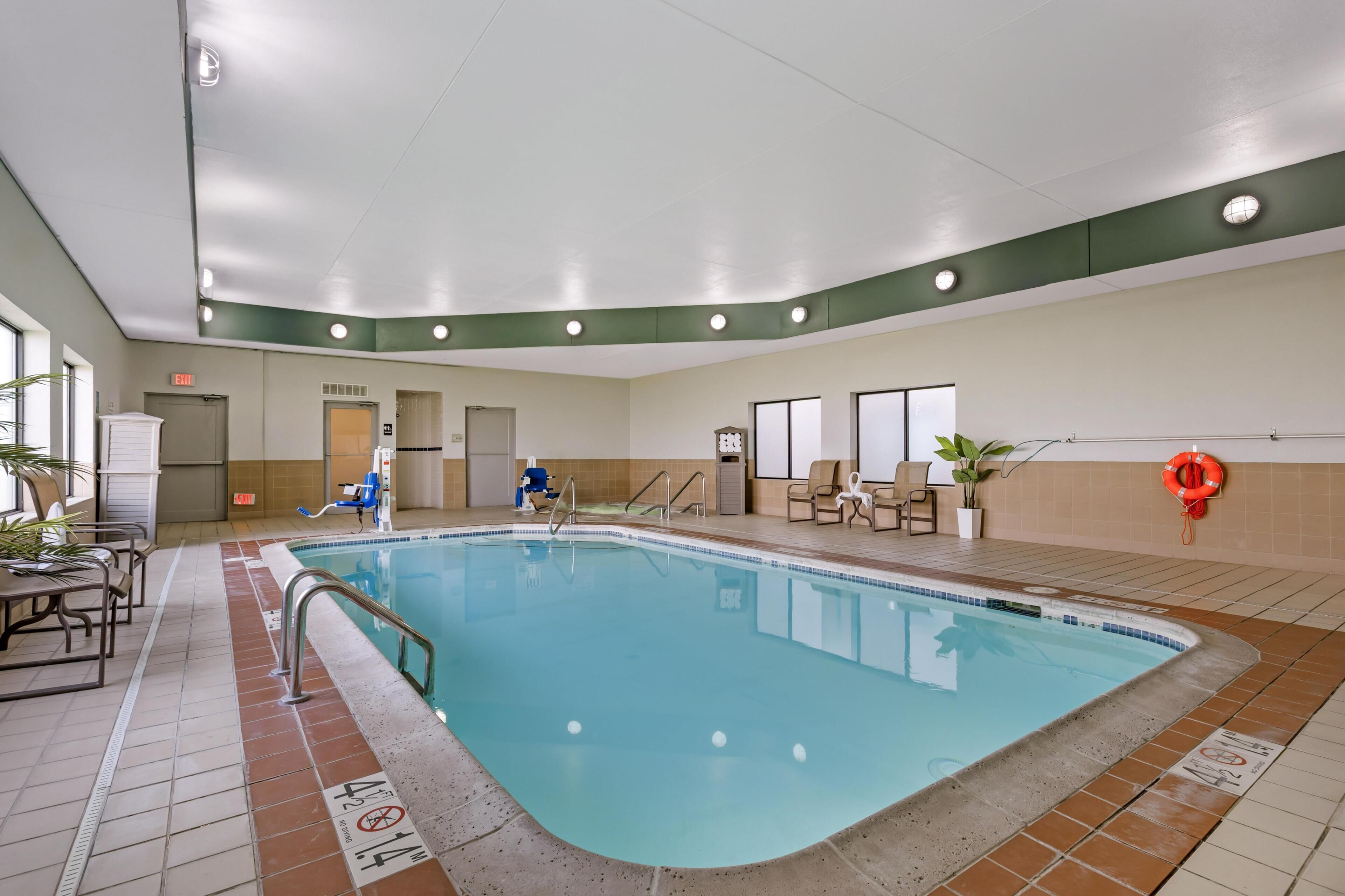 Piscina interna com piso cerâmico, um boia e uma cadeira à beira da piscina.