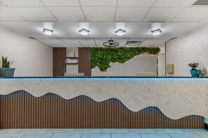 A reception desk with a marble top, a wooden slatted design below, and a green plant wall behind. - Best Western Plus Omaha Airport Inn (Carter Lake)