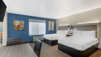 Ein Hotelzimmer mit zwei Betten, einem Schreibtisch und einem Sessel.