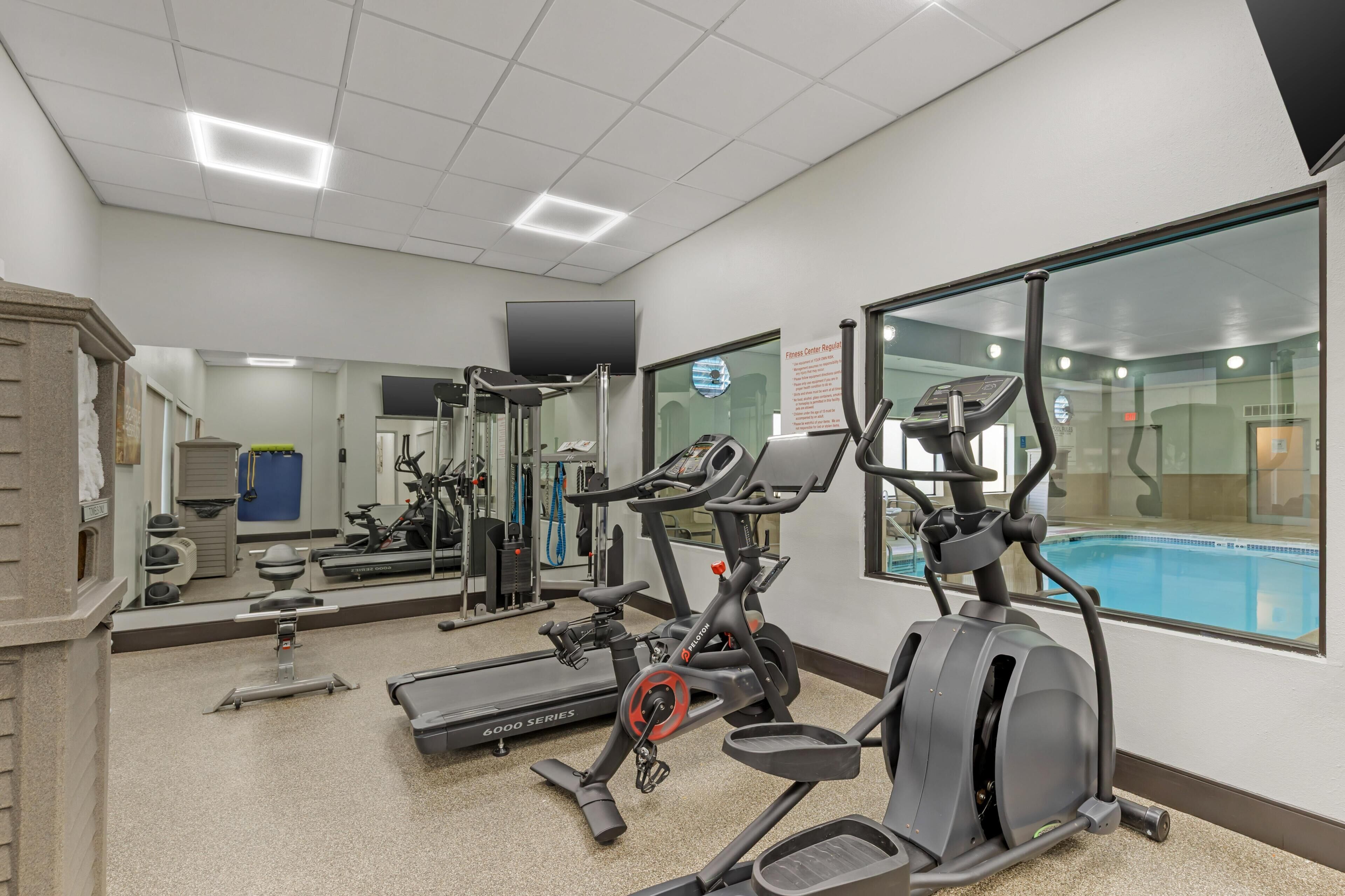 A fitness center with cardio machines, a pool, and a mirrored wall.