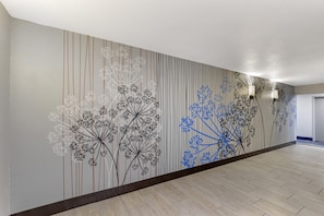 A hallway with a patterned wall and a wooden floor.