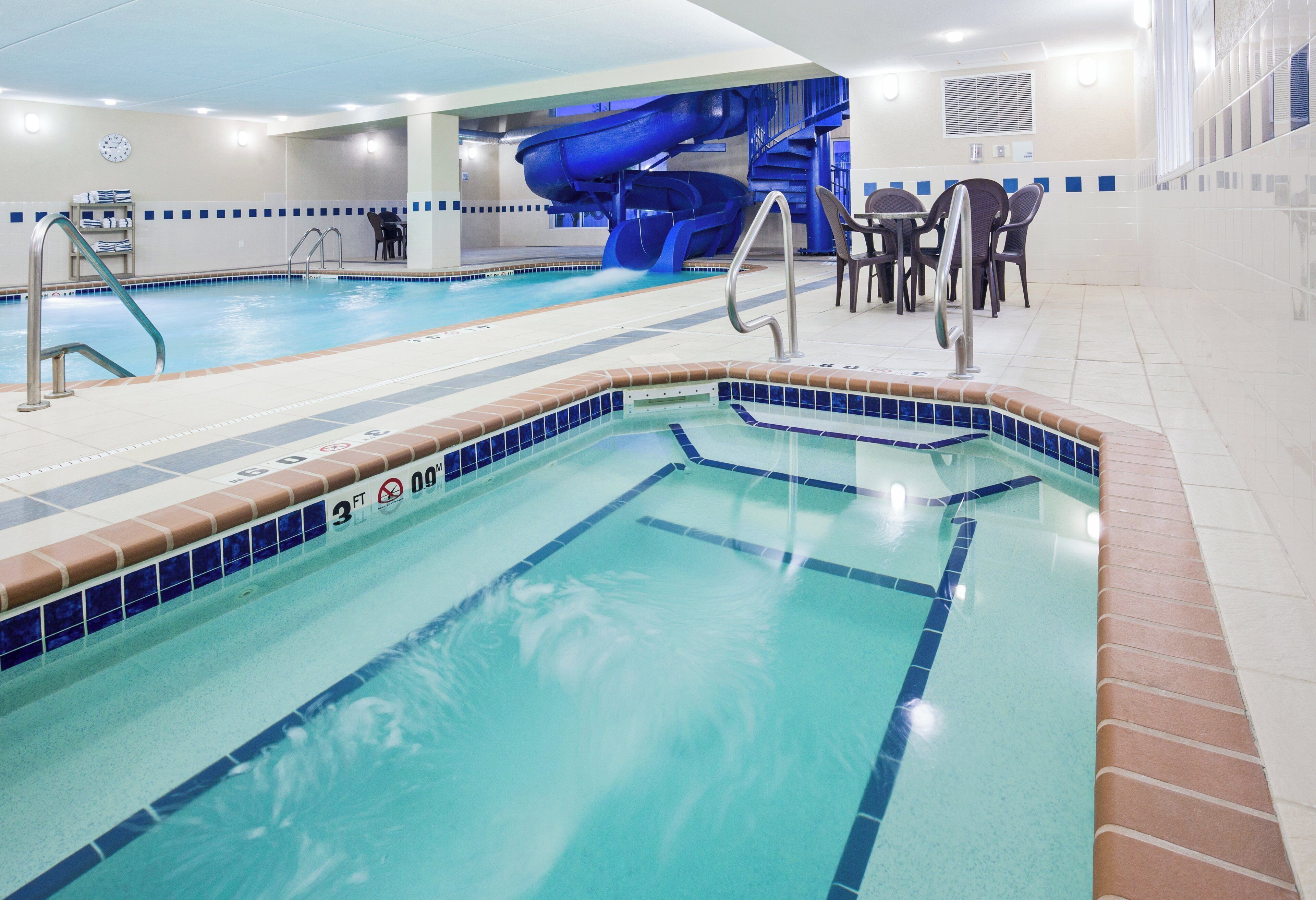 A swimming pool with a blue slide and a separate hot tub area.