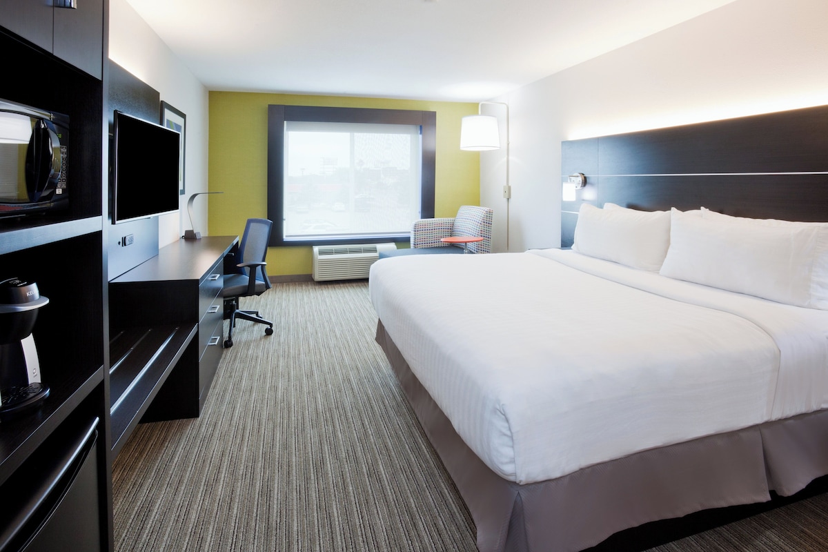 Une chambre d’hôtel équipée d’un lit, d’un bureau, d’une chaise, d’une télévision et d’une fenêtre donnant sur un paysage agréable.