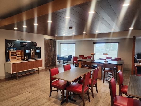 Un café moderne avec un plancher en bois, des chaises rouges et de nombreuses tables.