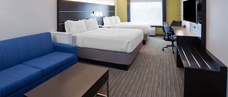 Una habitación de hotel con dos camas, un sofá azul, un escritorio y un televisor.