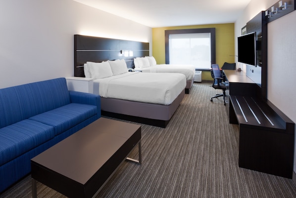 Une chambre d’hôtel avec deux lits, un canapé bleu, un bureau et une télévision.