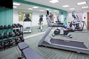 Un gimnasio con cintas de correr, elípticas y pesas.