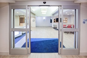 A hotel lobby with a blue carpet leading to a reception area, a non-smoking sign, and a seating area with red chairs. - Holiday Inn Express Hotel & Suites Dickinson by IHG (Dickinson)