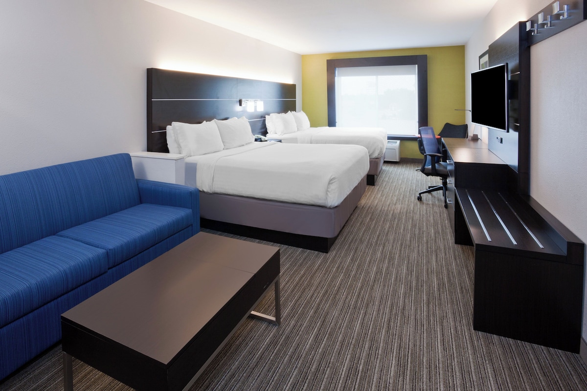 Une chambre d’hôtel avec un lit, un canapé, un bureau, une télévision et une fenêtre.