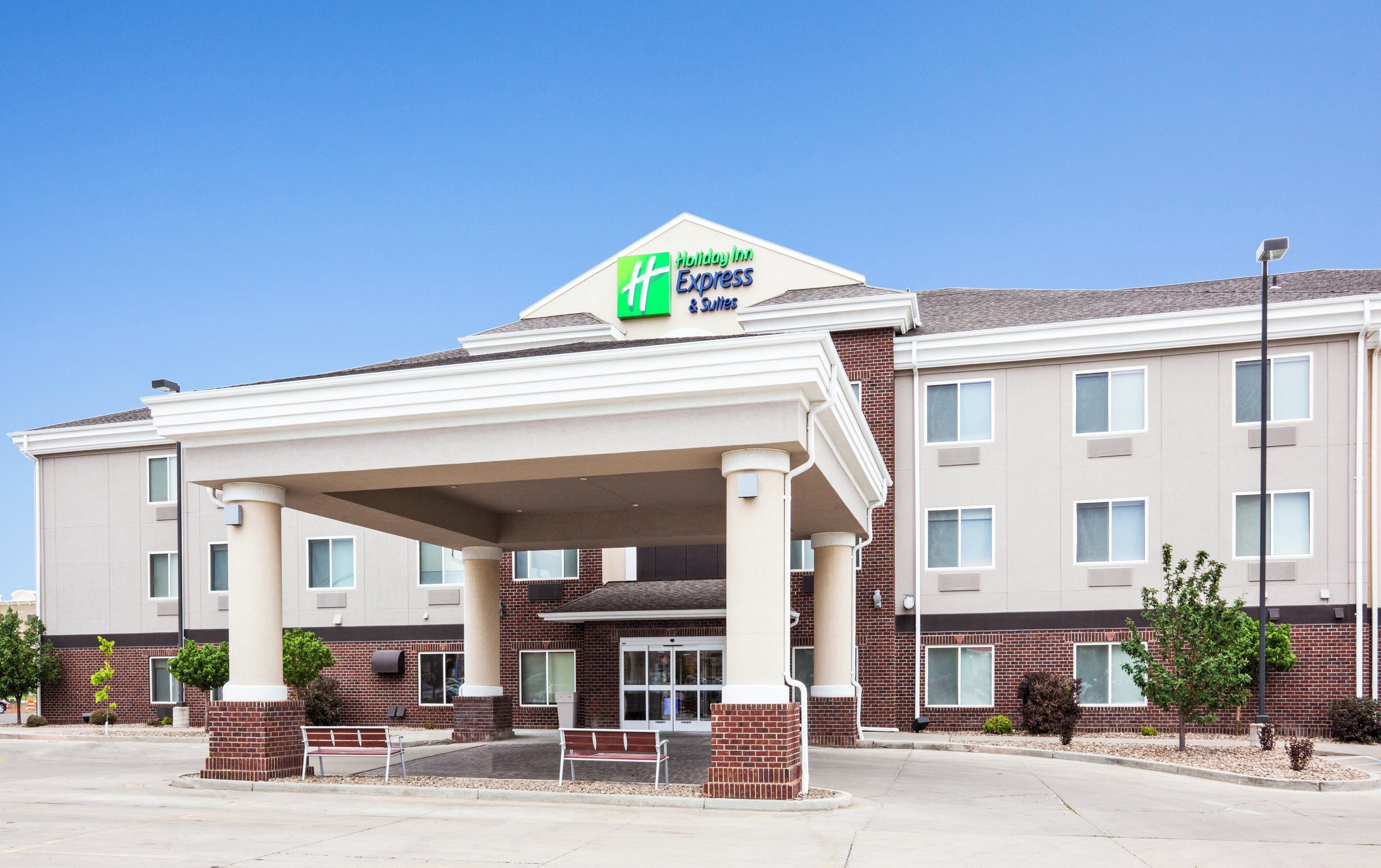 Un bâtiment de la chaîne Holiday Inn Express & Suites, doté d’une entrée abritée, d’une façade en briques et de nombreuses fenêtres.