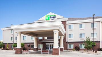 Un bâtiment de la chaîne Holiday Inn Express & Suites, doté d’une entrée abritée, d’une façade en briques et de nombreuses fenêtres.