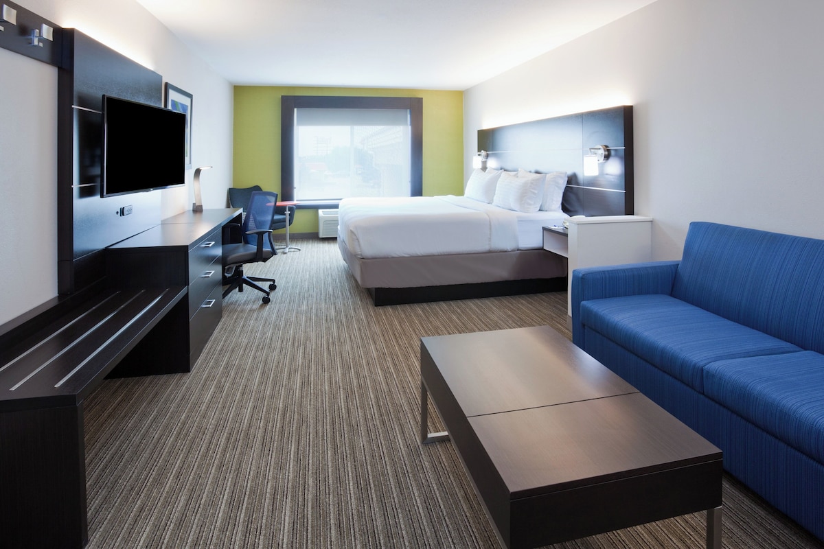Une chambre d’hôtel équipée d’un lit, d’une télévision, d’un bureau, d’une chaise, d’un canapé et d’une fenêtre.