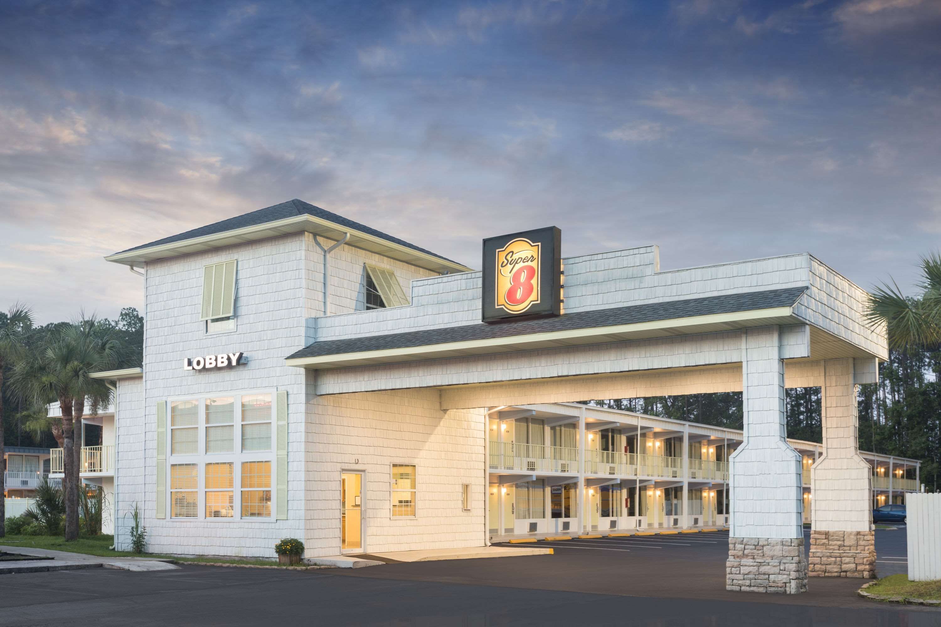 Hotel met een 'Super 8' bord, een lobby en een gebouw met twee verdiepingen en balkons.