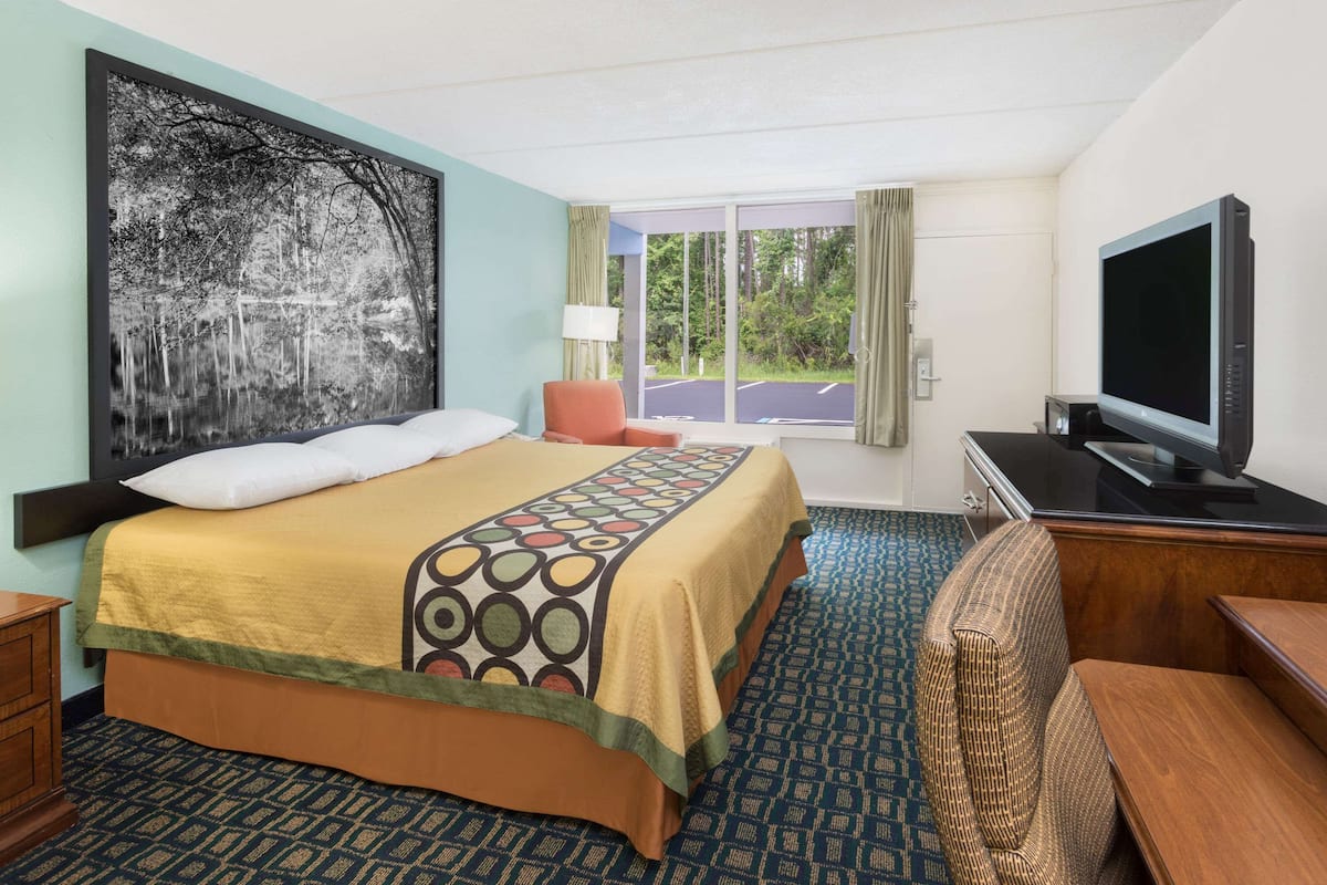 Une chambre d’hôtel avec un grand lit, une télévision, un bureau et une vue sur l’extérieur.