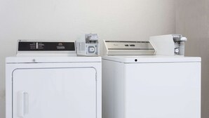 Two white washing machines with control panels, one with a front door and one without.