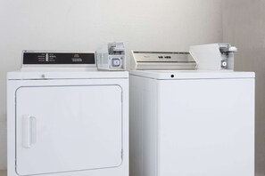 Two white washing machines with control panels, one with a front door and one without.
