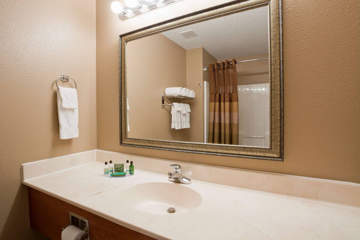 Un baño con lavabo, espejo y perchero para toallas.