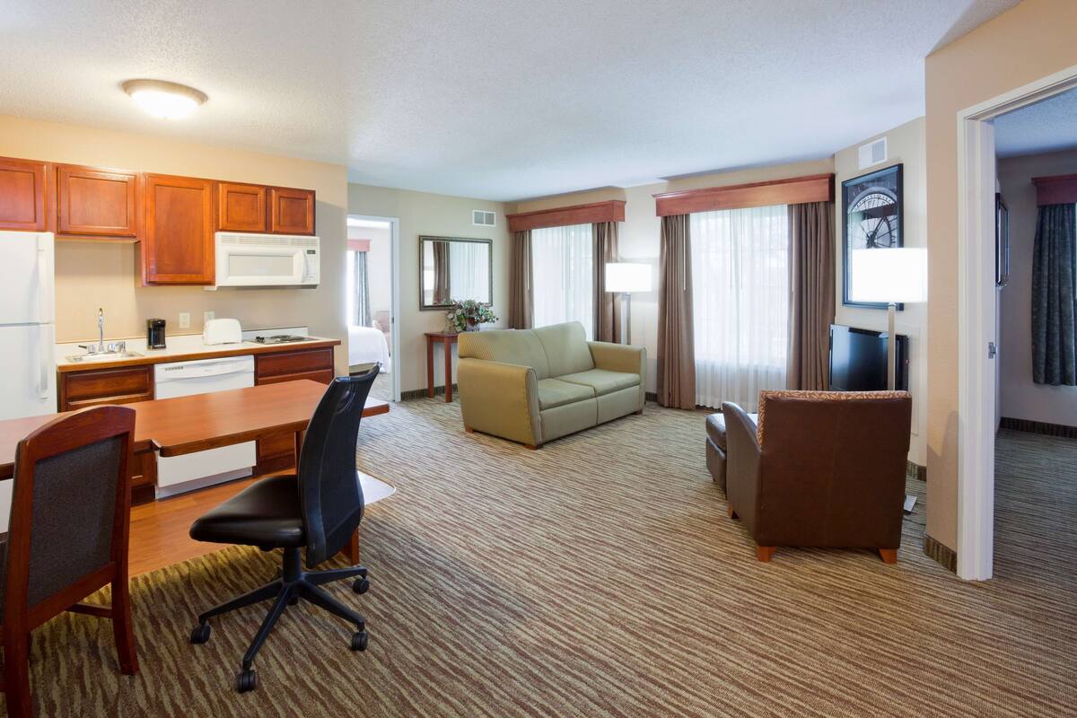 Una habitación de hotel con kitchenette, un sofá, una silla y un televisor.