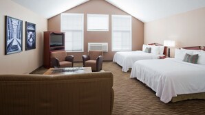 A hotel room with two beds, a TV, a sofa, and a dining table. - GrandStay Residential Suites - Eau Claire (Eau Claire)