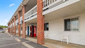 A motel with a parking lot, brick pillars, white railings, and a Coca-Cola vending machine. - Americas Best Value Inn Biddeford Portland (Biddeford)