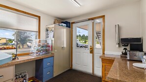A compact kitchen with a window, a refrigerator, a microwave, and a sink. - Americas Best Value Inn Biddeford Portland (Biddeford)