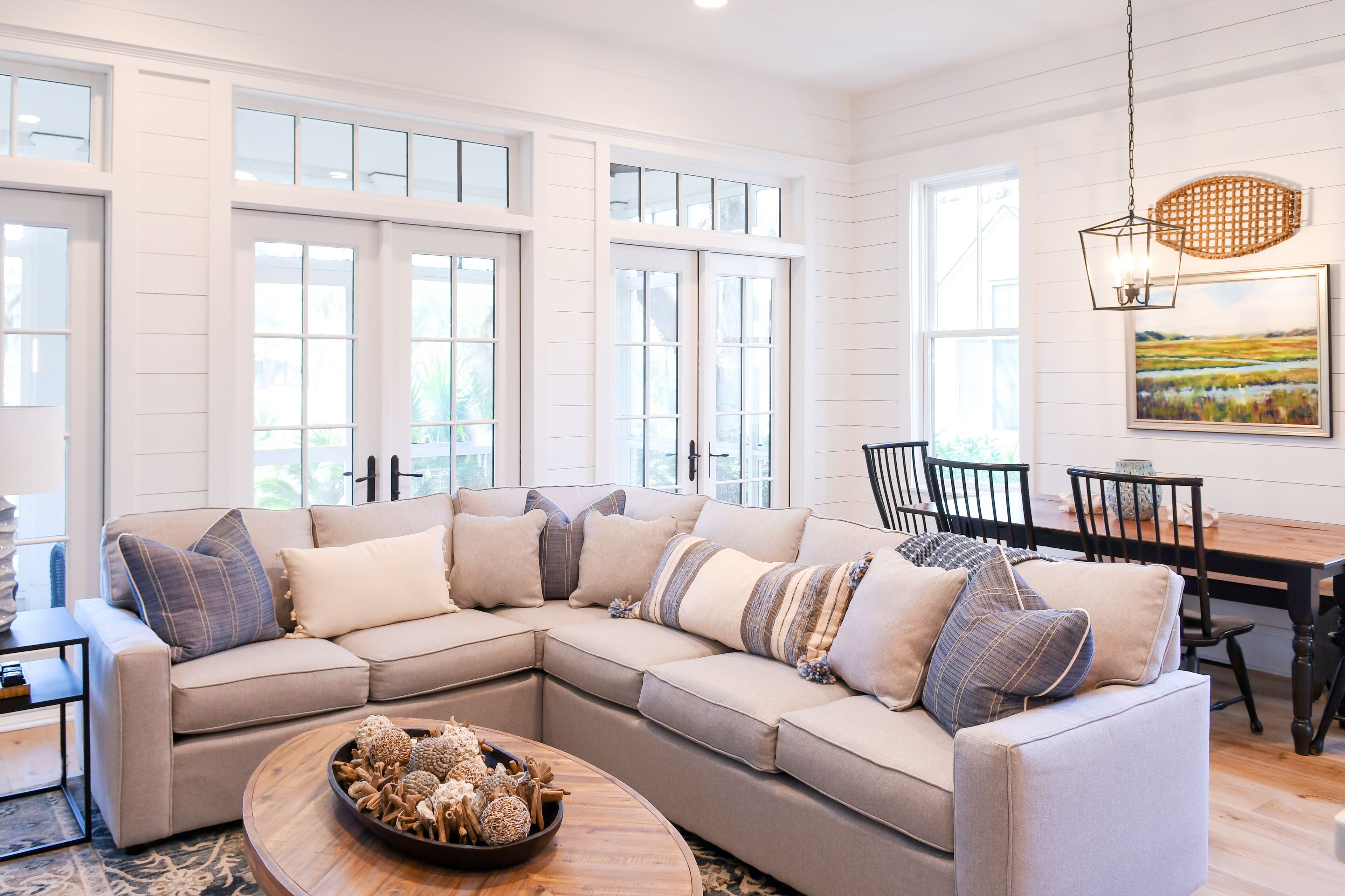 A spacious living room with a large sectional sofa, a wooden coffee table, and a dining area with a wooden table and chairs.