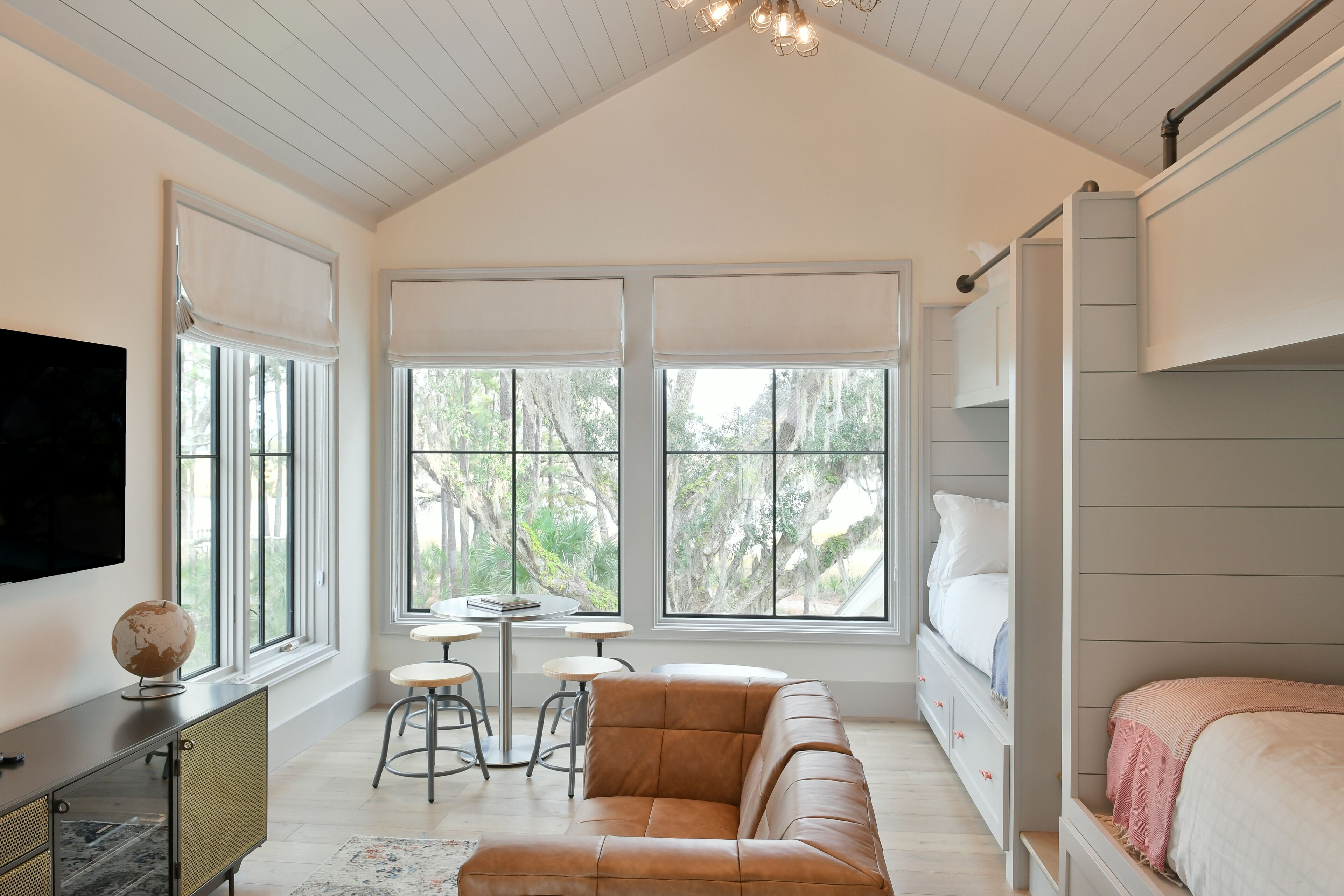 Une chambre moderne avec une grande fenêtre, un canapé, un lit et un téléviseur.