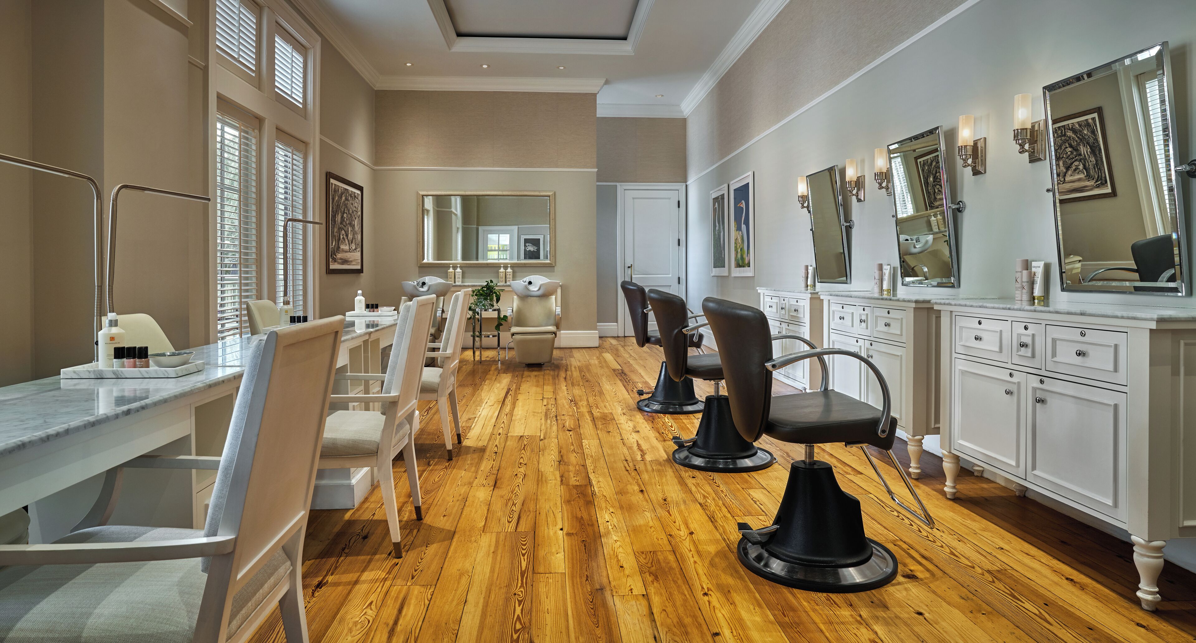 A salon with multiple hairdressing chairs, a marble countertop, and a wooden floor.