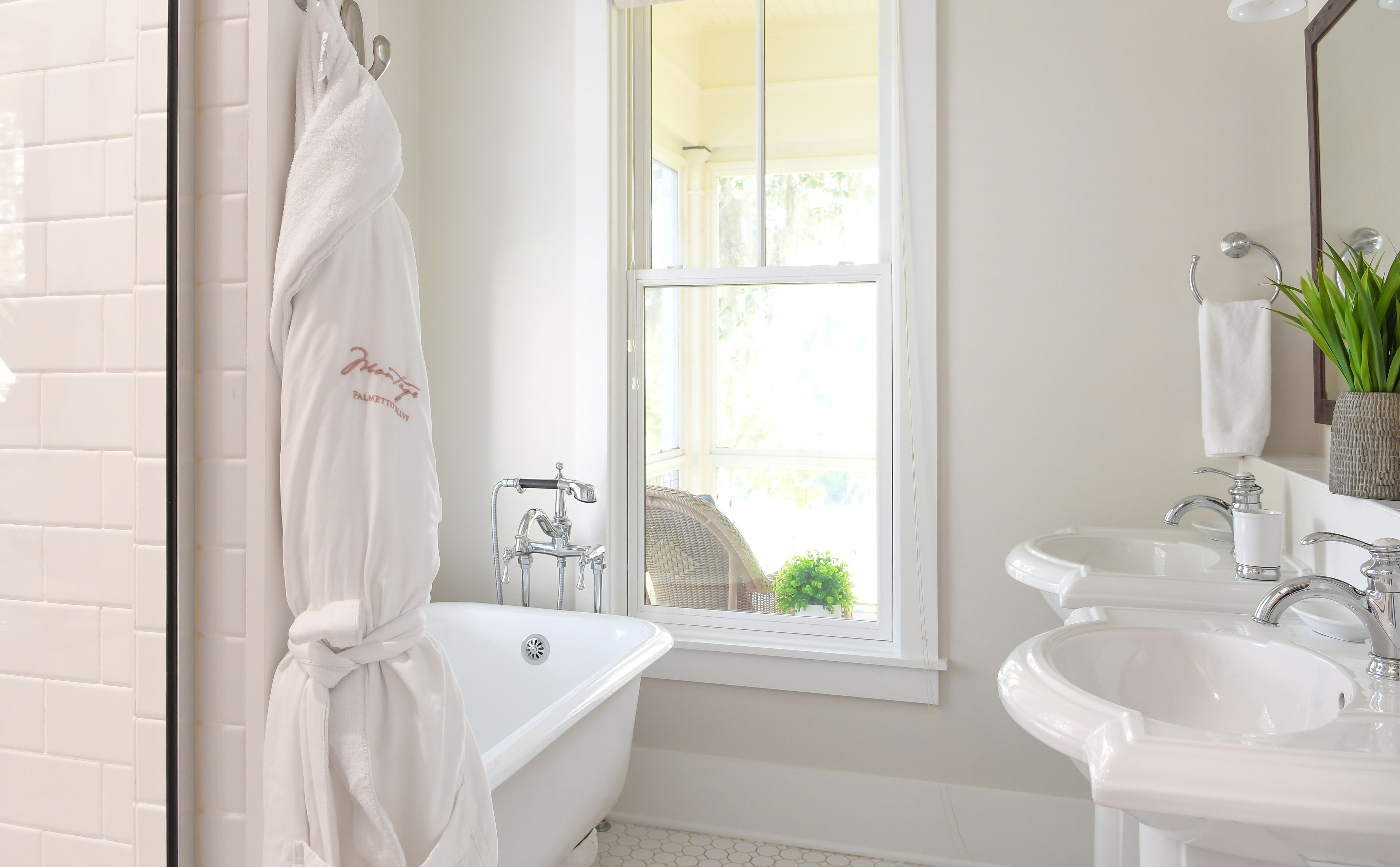 Une salle de bain moderne avec une baignoire, deux lavabos, une fenêtre et un miroir.