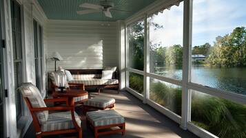 Eine überdachte Veranda mit Holzmöbeln, großen Fenstern und Seeblick.