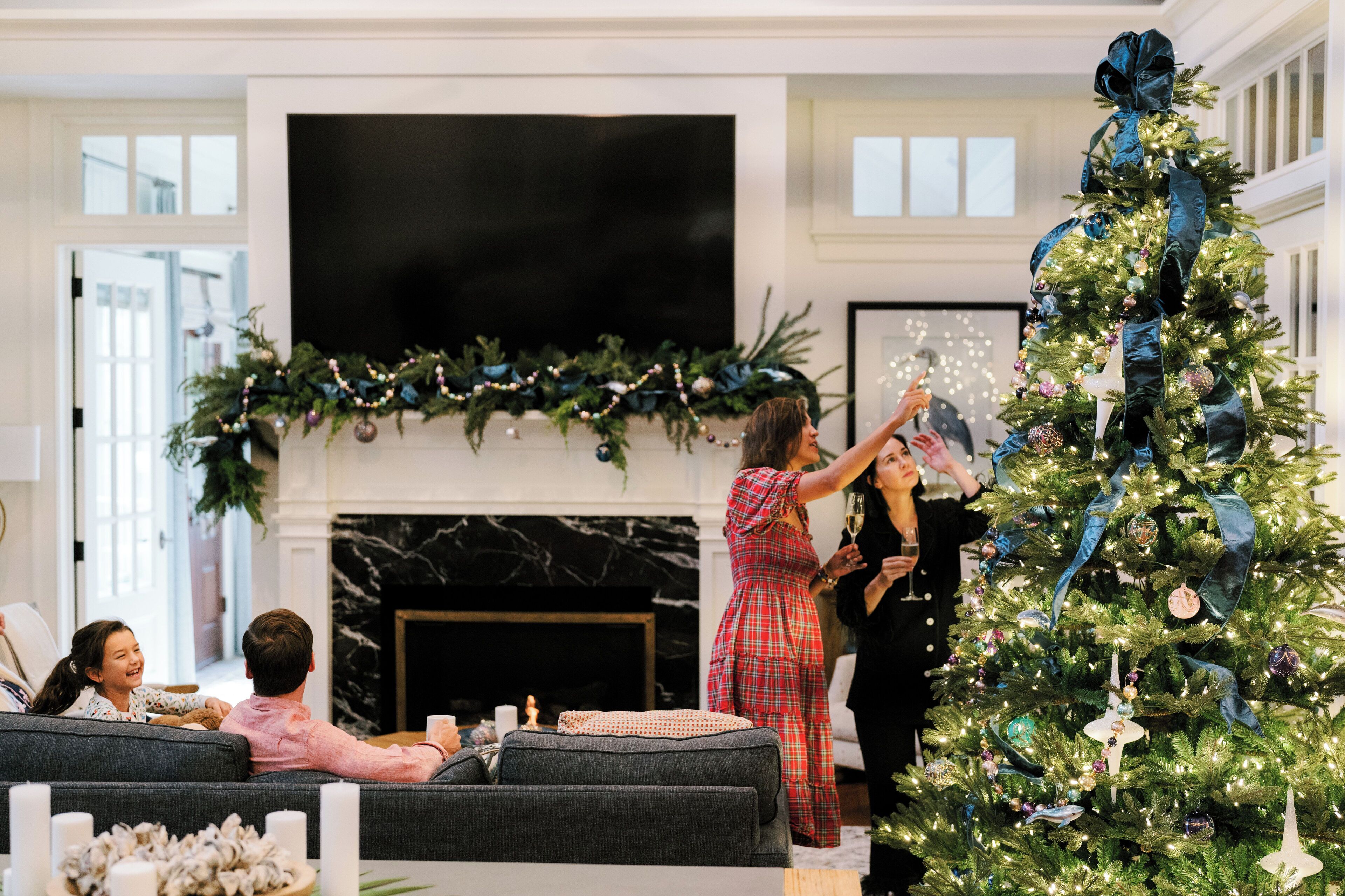 Een woonkamer met een kerstboom, een open haard en een televisie.
