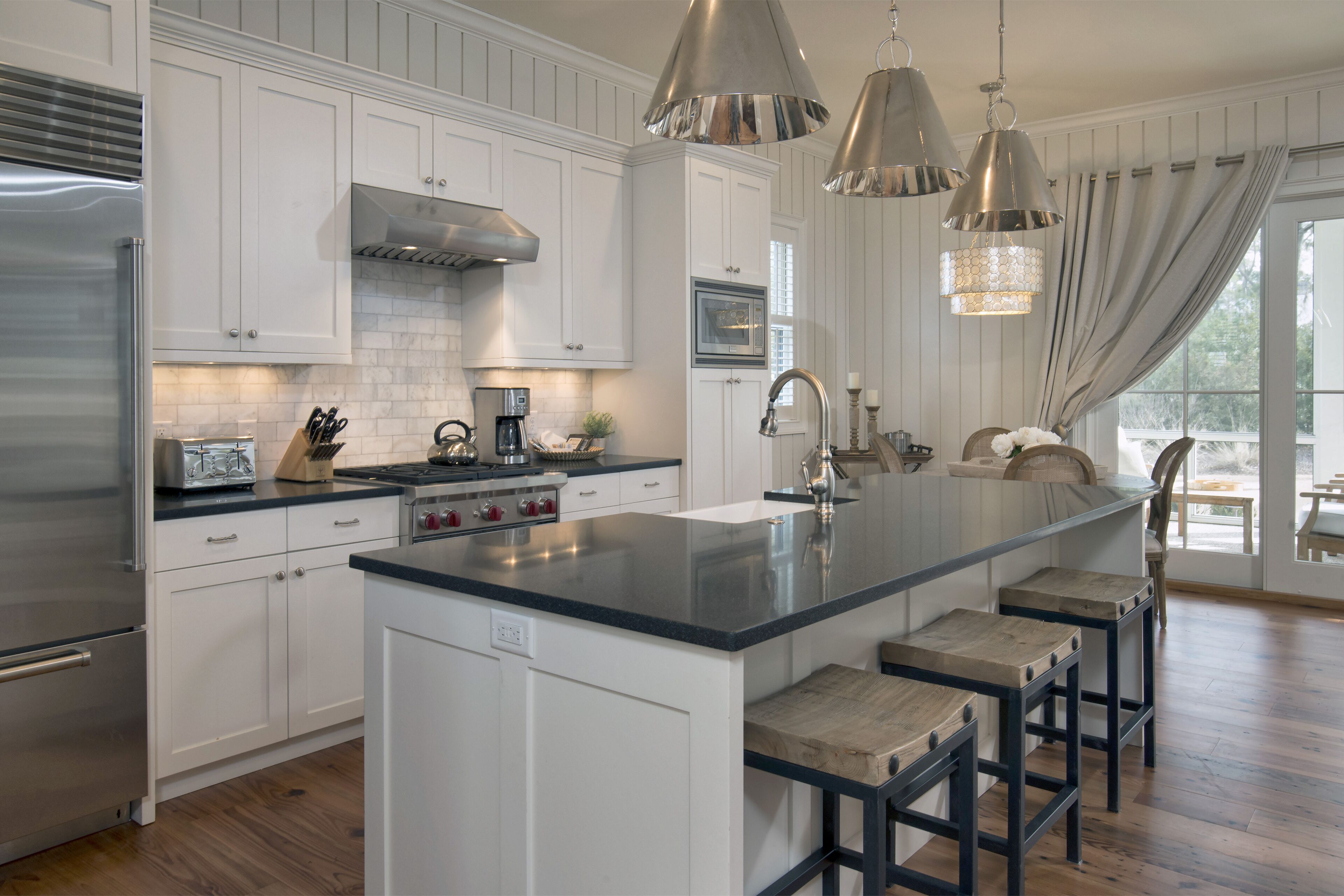 A modern kitchen with white cabinetry, stainless steel appliances, and a central island with bar stools.
