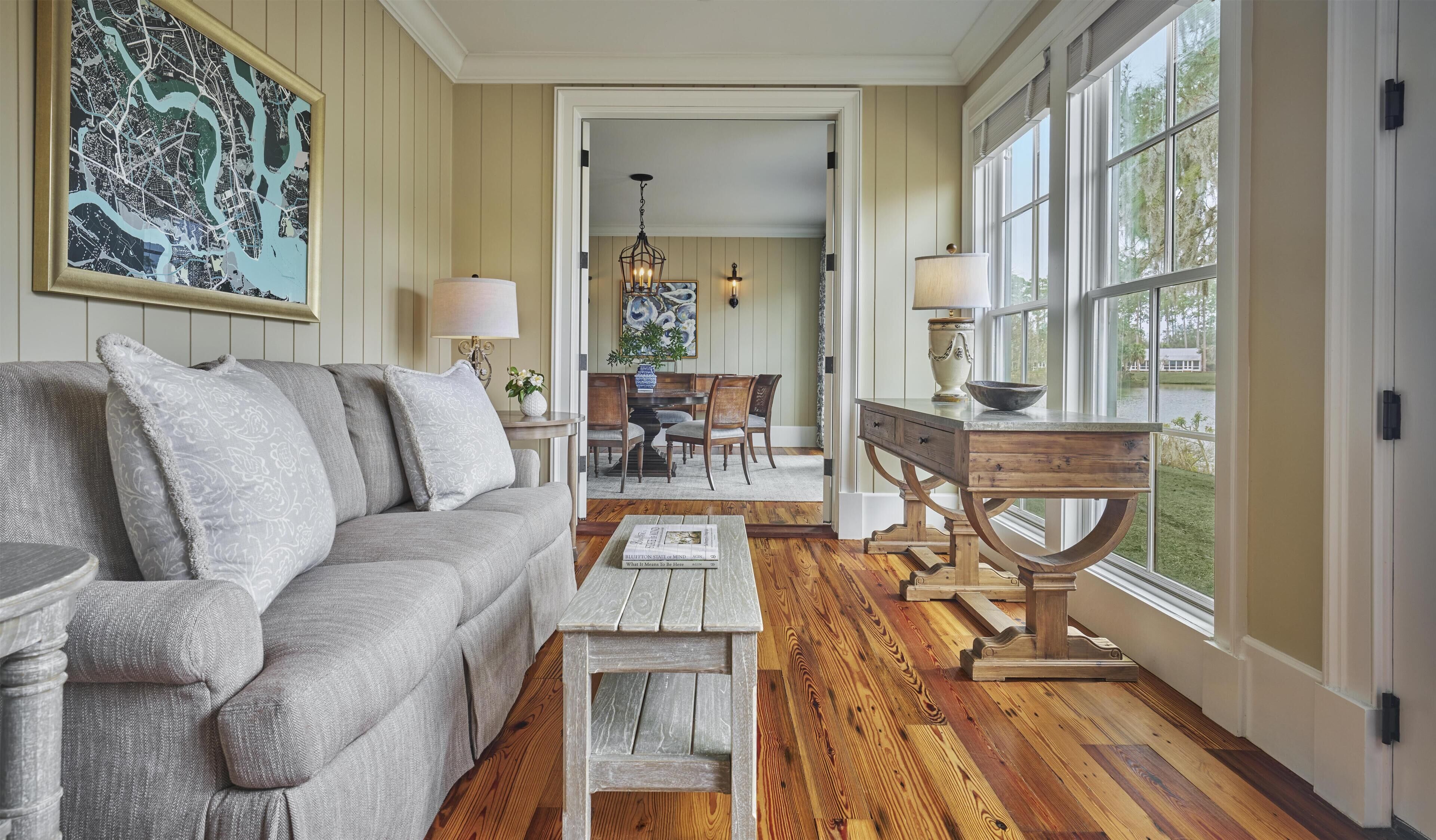 A room with a sofa, a coffee table, a dining table with chairs, and a large window.