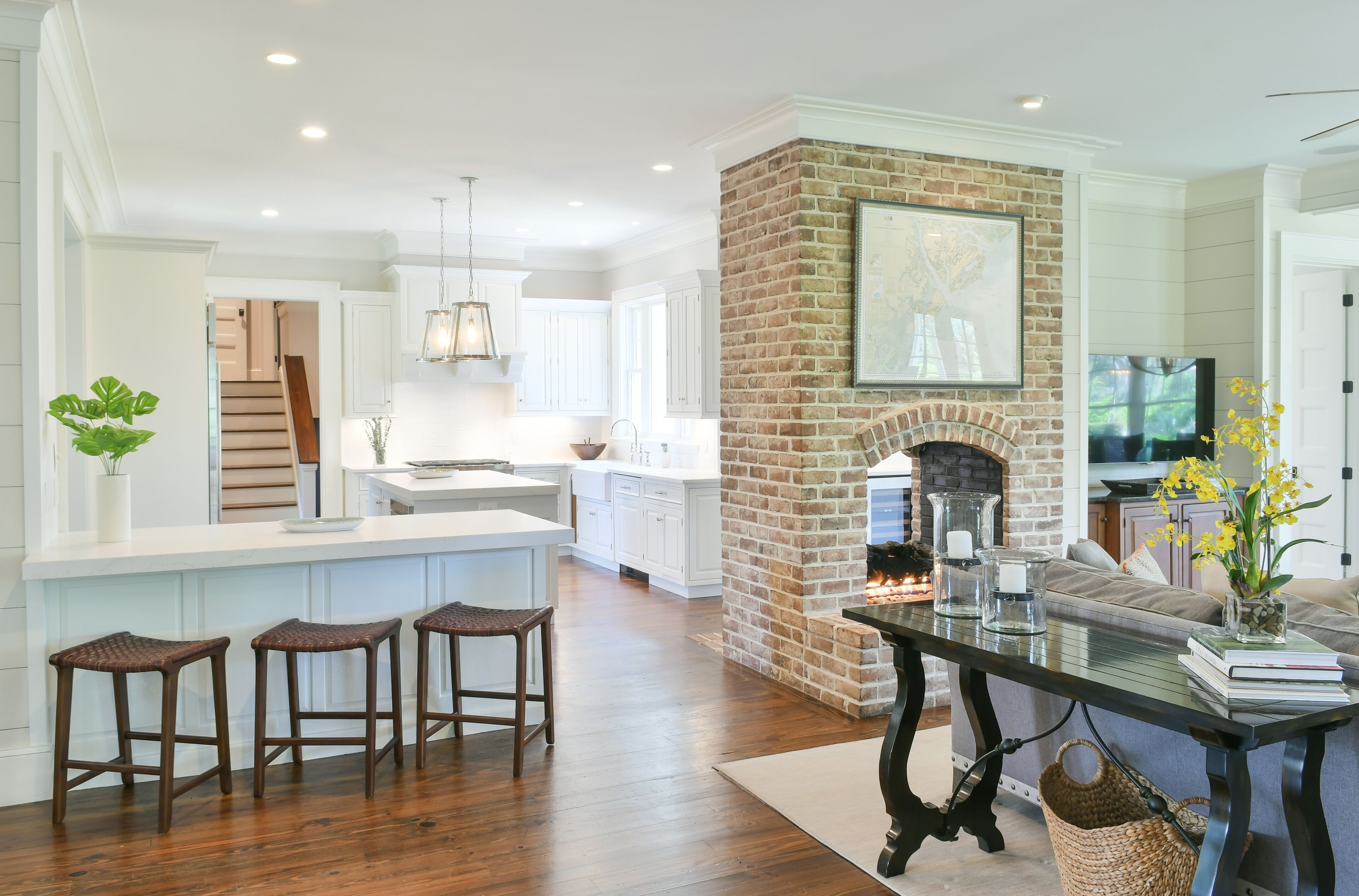 A spacious living area with a fireplace, a kitchen with white cabinets, and a dining area with stools.
