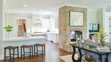 A spacious living area with a fireplace, a kitchen with white cabinets, and a dining area with stools.
