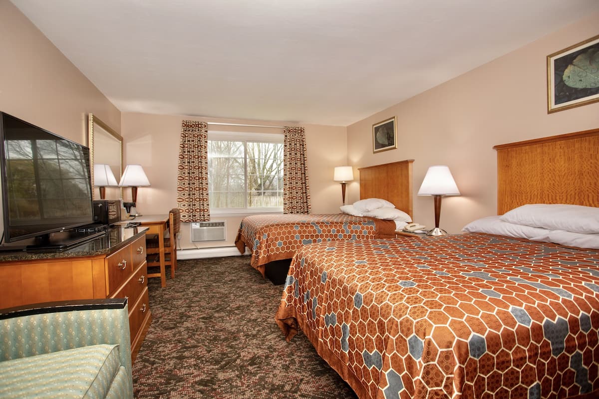 A hotel room with two beds, a TV, a desk, and a chair.