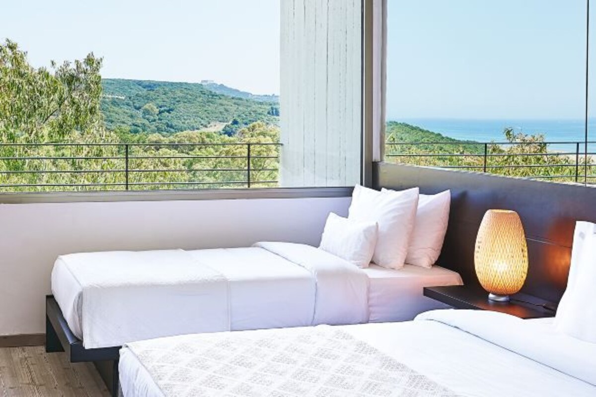 Une chambre d’hôtel avec deux lits, une vue sur la mer et un balcon.