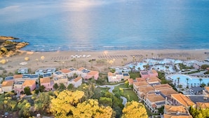 Vue aérienne d’une station balnéaire comprenant plusieurs bâtiments, une plage et un espace piscine.