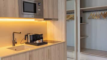 Una cocina moderna con armarios de madera, microondas integrado, cafetera y pileta.