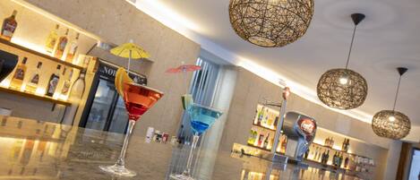 Una zona de bar con una encimera de mármol pulido, dos vasos de martini y un dispensador de Coca-Cola.