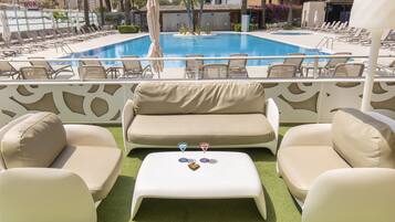 Un área junto a la piscina con piscina, sillas de descanso, un sofá y una mesa pequeña con dos copas de martini.
